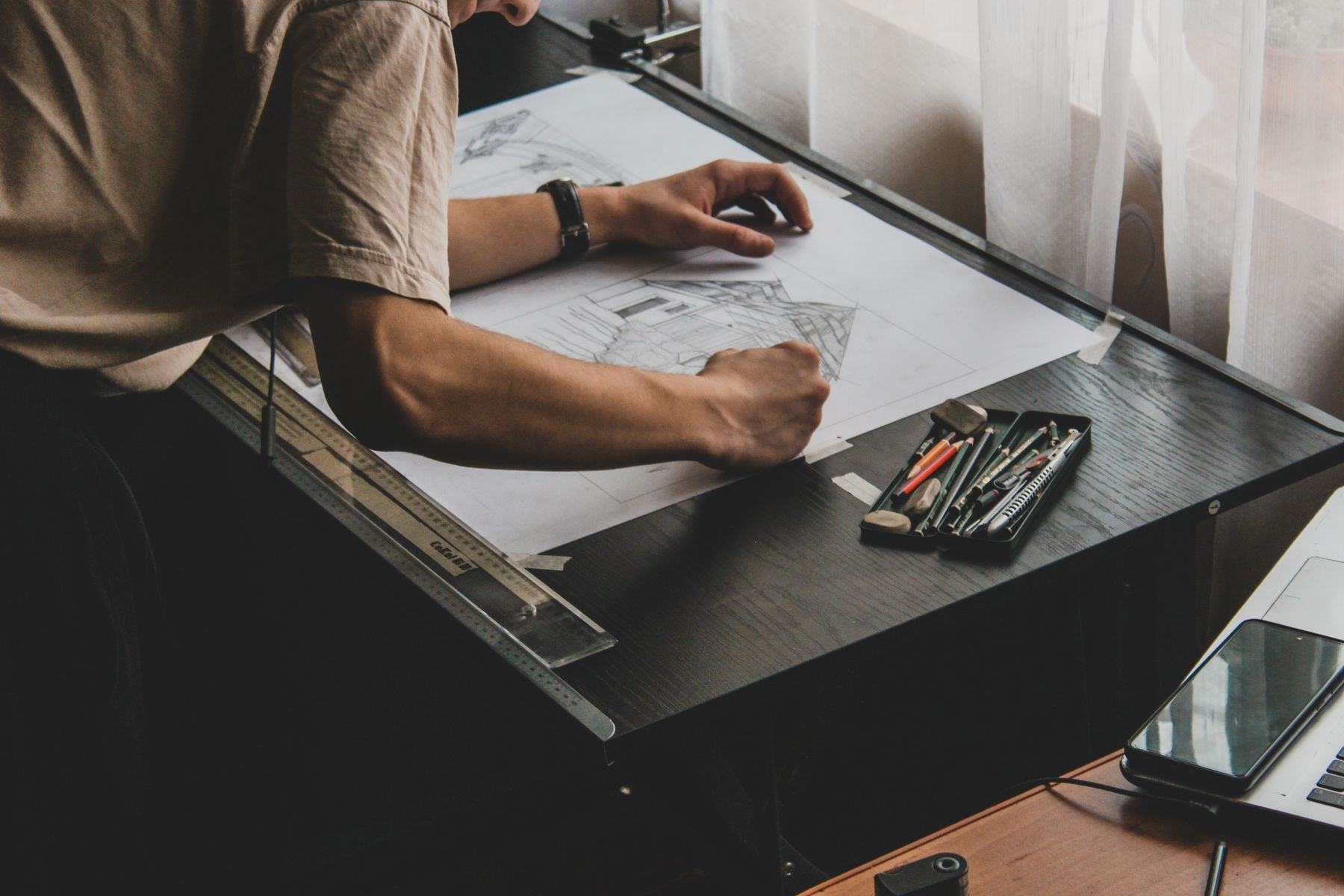 A designer sketching at a drafting table